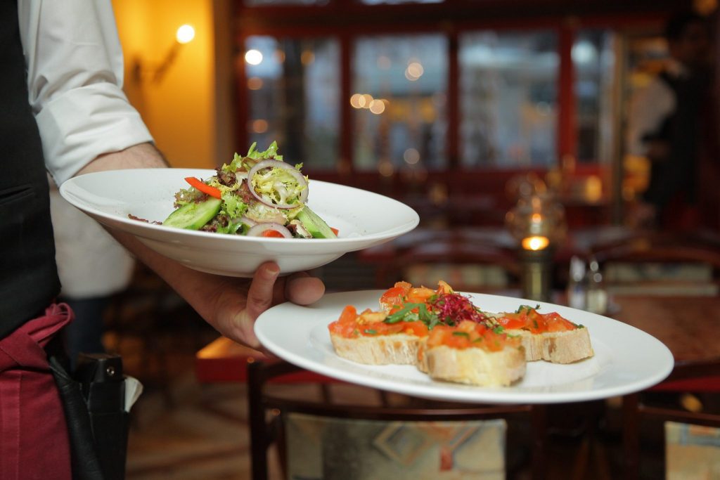 Kelner niosący dwa talerze z przystawkami na sali restauracji